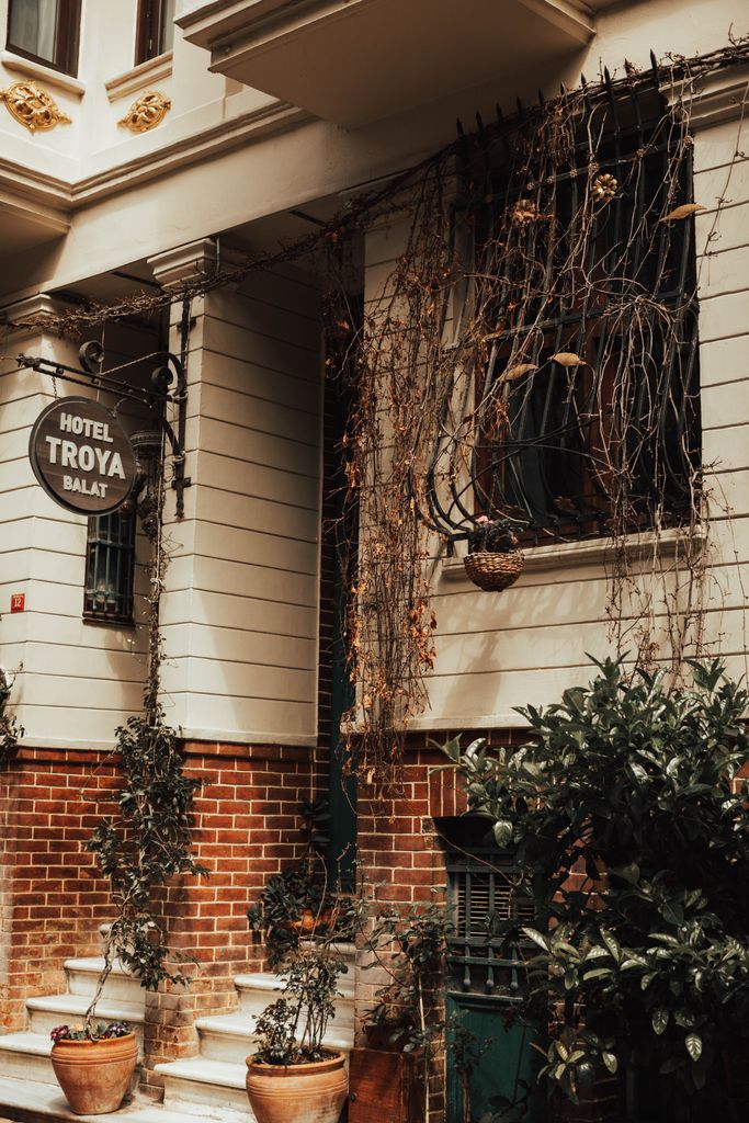 A quaint exterior of Hotel Troya Balat adorned with lush greenery and rustic charm.