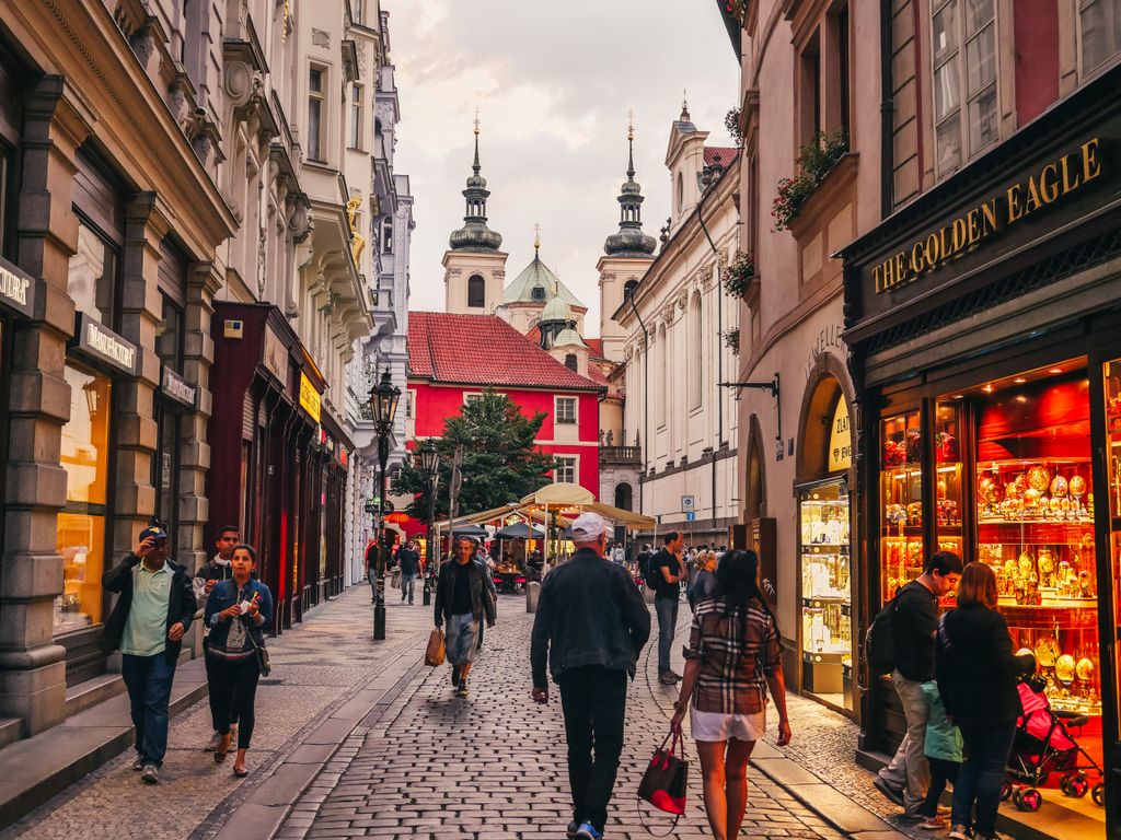 Charming cobblestone street in Prague's Old Town with tourists and historic architecture.