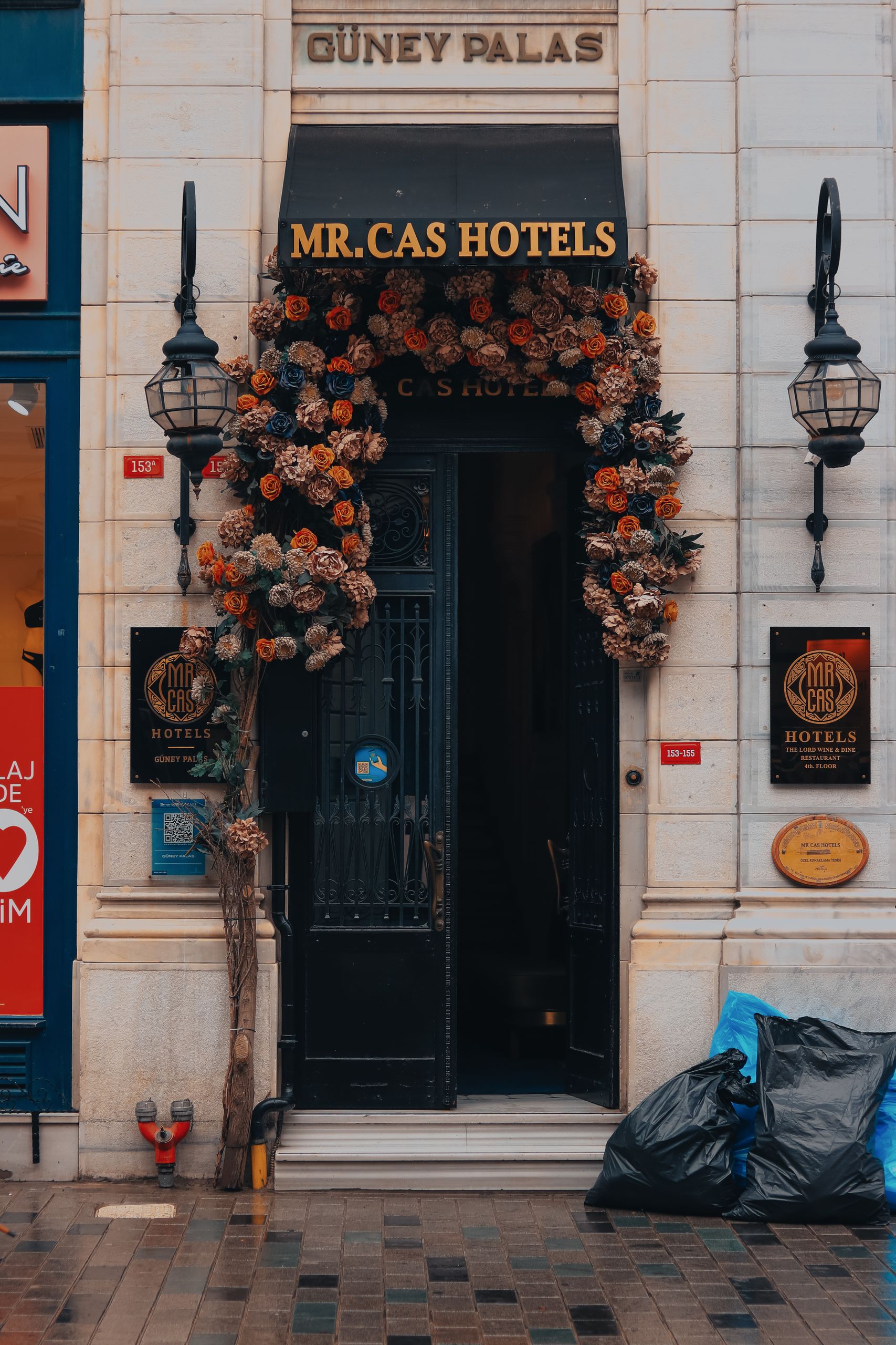 Elegant hotel entrance decorated with flowers, street lamps, and signage.
