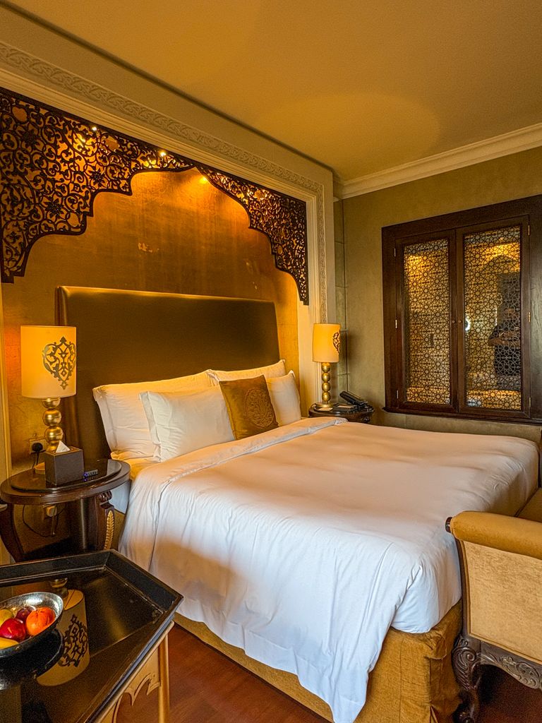 Elegant hotel room in Dubai with ornate decor and plush bedding.